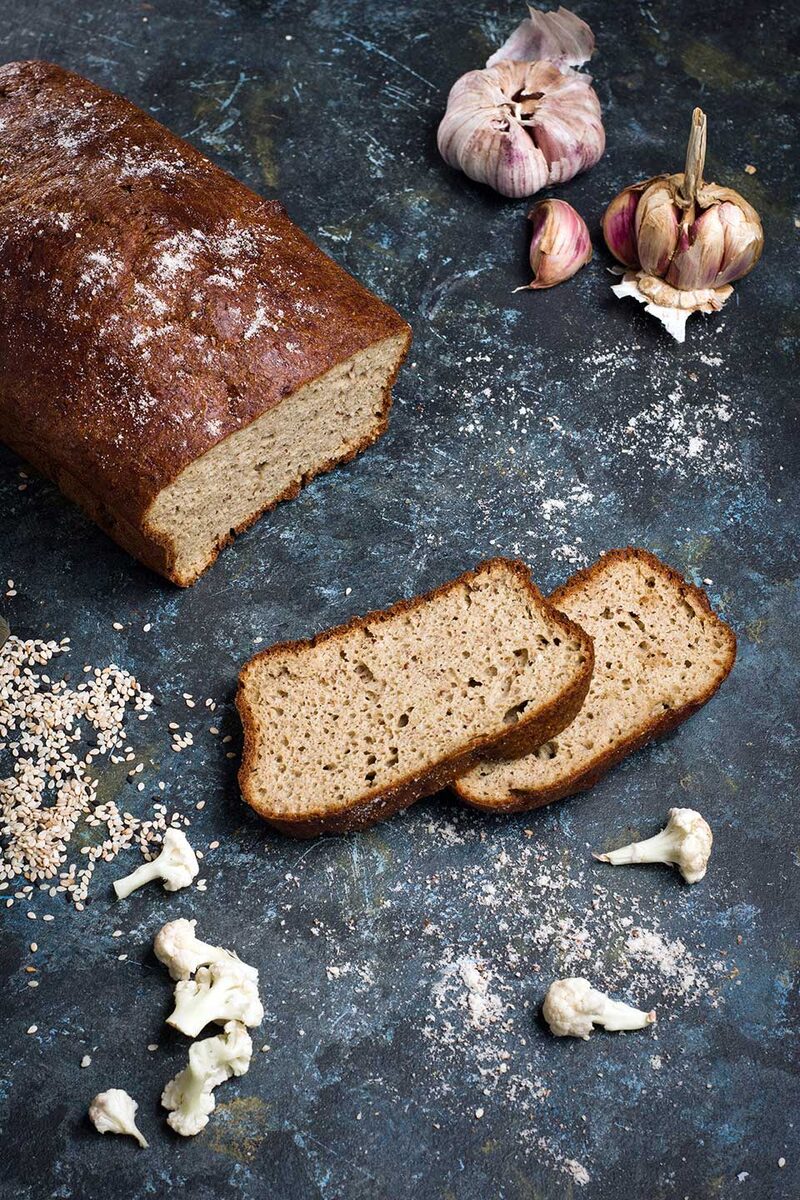 Sliced walnut and raisin loaf cake on a wooden board, overhead