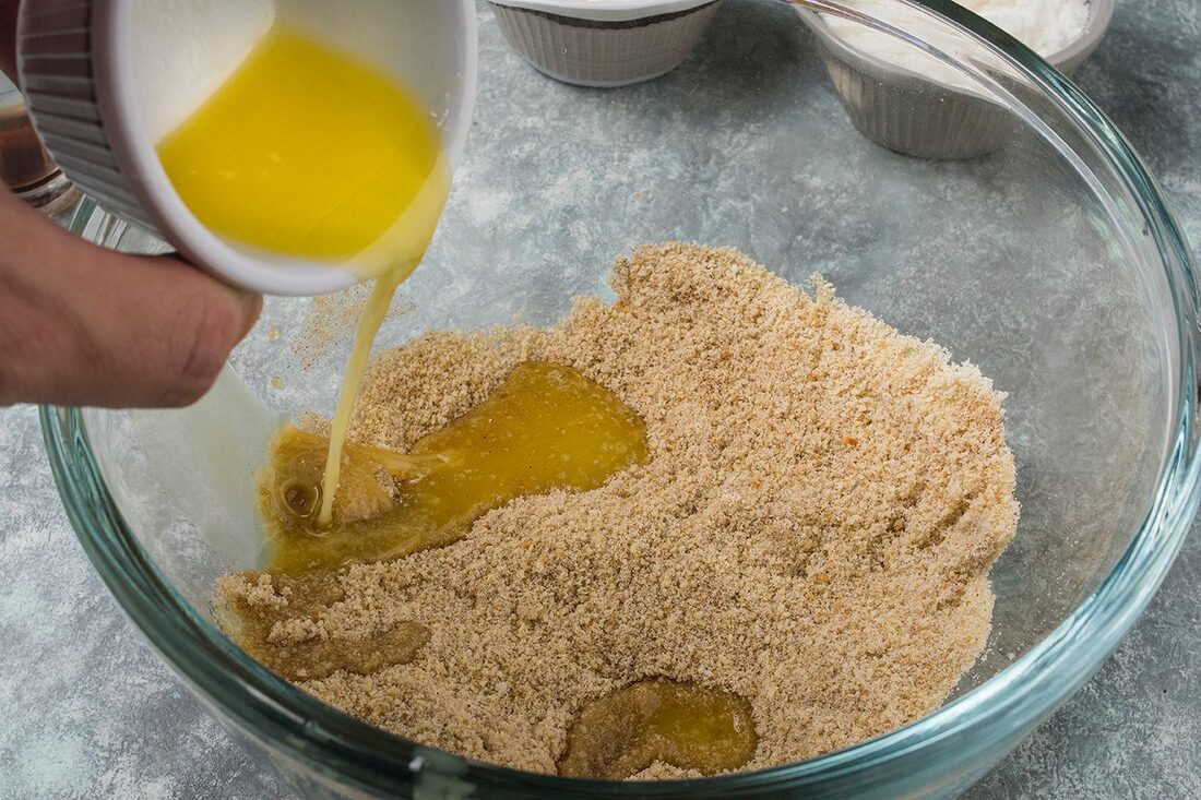 Pouring melted butter into the crumb base